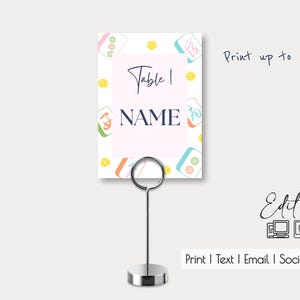 May include: A pink and white table number card with a colorful mahjong tile pattern. The card says "Table 1" and "NAME" in black text. The card is designed to be printed up to 5x7 inches.