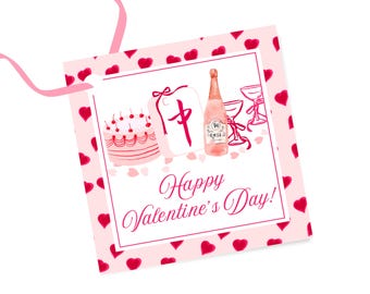 Puede incluir: Etiqueta de regalo rosa con un pastel rosa y blanco, una botella de vino rosado y dos copas de champán. La etiqueta está decorada con corazones rosas y el texto "¡Feliz Día de San Valentín!"
