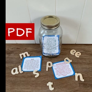 May include: A printable PDF download for a literacy game. The image shows a mason jar filled with wooden letter tiles and two cards with instructions for a "splat" game and "wonderful writing" activities.