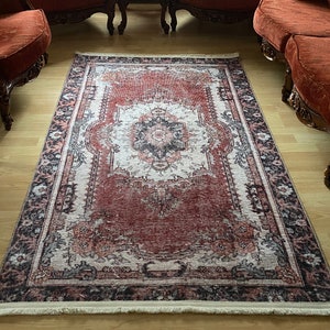 May include: A red and cream patterned rug with a fringed edge, placed in a living room with antique-style furniture.