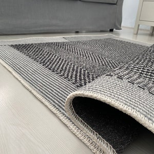 Pu&ograve; includere: Primo piano di un tappeto con motivo bianco e nero con un bordo bianco. Il tappeto &egrave; arrotolato e il bordo &egrave; visibile.