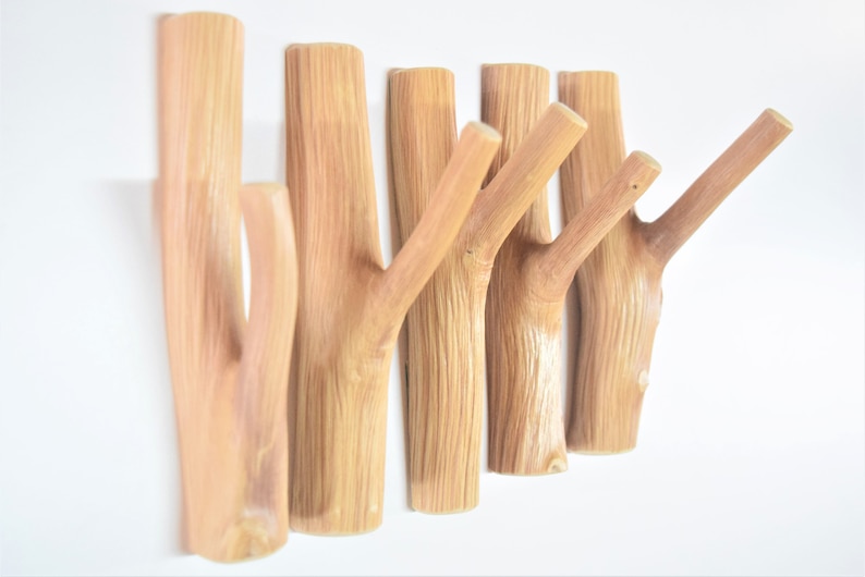 May include: A set of six wooden wall hooks, each shaped like a branch with a single hook. The hooks are made of natural wood and have a light brown color.