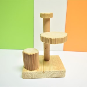 Puede incluir: Una plataforma de madera de tres niveles con un acabado de madera natural. La plataforma tiene una base cuadrada y dos plataformas redondas.