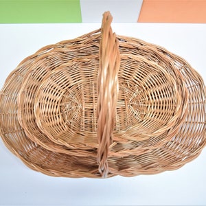 Pu&ograve; includere: Un set di tre cesti in vimini intrecciati con un manico. I cesti sono di forma ovale e sono annidati l'uno dentro l'altro.