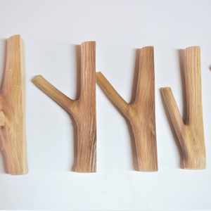 May include: Five wooden hooks in the shape of tree branches. The hooks are all natural wood color and have a rustic look.