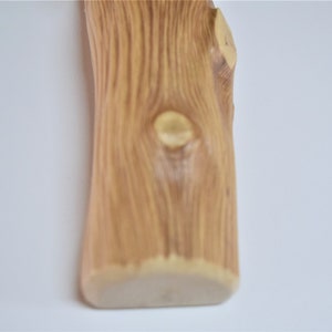 May include: A close-up of a wooden vase with a natural wood grain pattern. The vase has a rounded bottom and a slightly irregular shape.