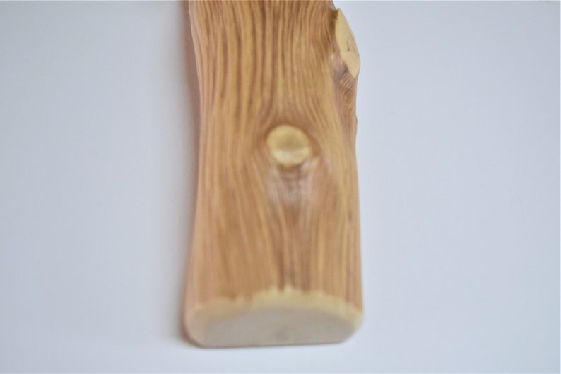 May include: A close-up of a wooden vase with a natural wood grain pattern. The vase has a rounded bottom and a slightly irregular shape.