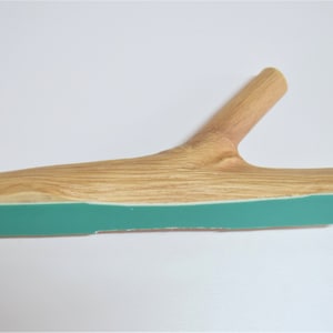 May include: A wooden branch with a teal green strip on the bottom. The branch has a natural wood finish and is shaped like a Y.