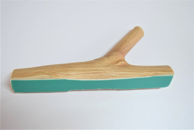 May include: A wooden branch with a teal green strip on the bottom. The branch has a natural wood finish and is shaped like a Y.