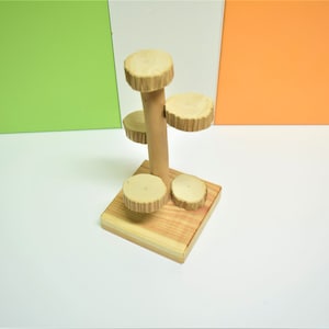 Pode incluir: Uma árvore de brinquedo de madeira com quatro plataformas para pequenos animais escalarem. A árvore é feita de madeira natural e tem uma cor castanho claro.