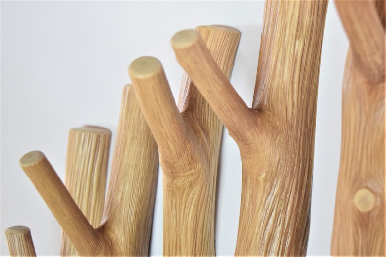 May include: A wooden wall-mounted coat rack with multiple branches, resembling a tree, for hanging clothes, hats, or bags.