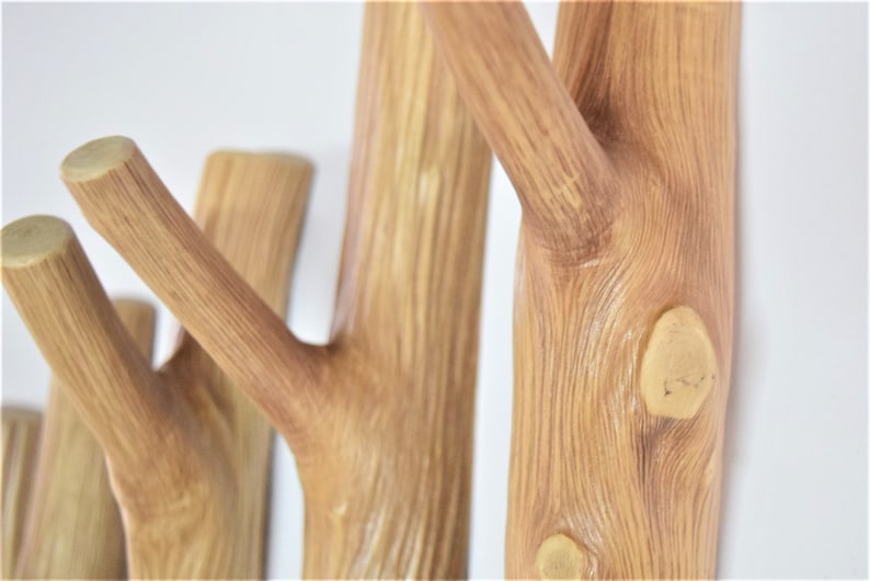 May include: A wooden wall-mounted coat rack with multiple branches, resembling a tree. The branches are finished in a light brown color and have a natural wood grain texture.