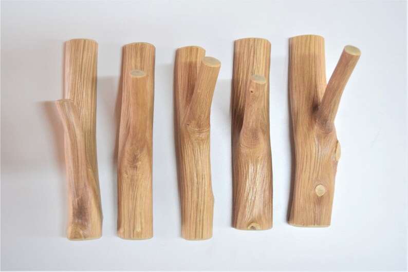 May include: Five wooden hooks made from natural branches, each with a unique shape and grain pattern. The hooks are ideal for hanging coats, hats, or other items in a rustic or farmhouse style.