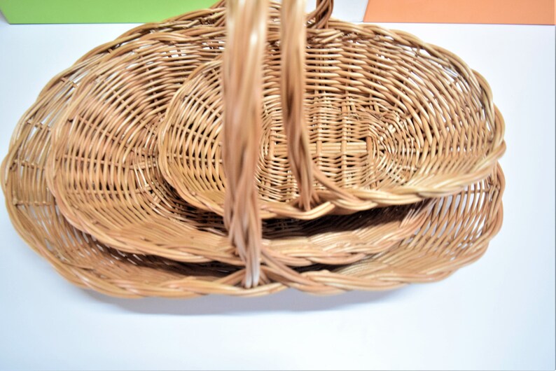 Pu&ograve; includere: Un set di tre cesti ovali in vimini con manici. I cesti sono annidati l'uno dentro l'altro, con il cestello pi&ugrave; grande in basso e il cestello pi&ugrave; piccolo in alto.