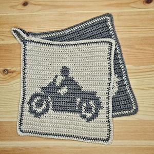 May include: Two crocheted pot holders with a gray motorcycle design on a beige background. The pot holders have a gray border.