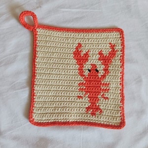 May include: A crocheted pot holder with a red lobster design. The pot holder has a loop for hanging.