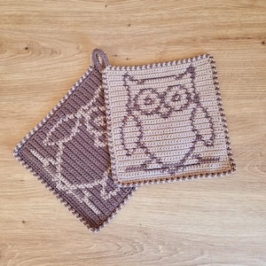 Może przedstawiać: Dwa szydełkowe uchwyty na garnki z wzorem sowy. Jeden uchwyt jest brązowy, a drugi beżowy.