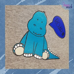 May include: A light gray t-shirt with a blue dinosaur graphic and a blue speech bubble that says "ROAR!!!".