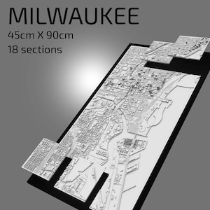 May include: A white 3D model of the city of Milwaukee, Wisconsin, made up of 18 sections. The model is 45cm x 90cm and is displayed on a black background.