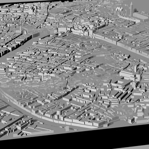 Op de afbeelding: Een 3D-model van een stad met gebouwen en straten. Het model is gemaakt van grijs plastic en is ontworpen om eruit te zien als een echte stad.