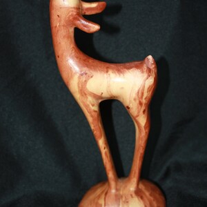May include: A ceramic deer figurine with a light brown and reddish-brown marbled glaze. The deer is standing on its hind legs with its head tilted up.