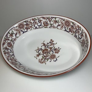 May include: White oval serving bowl with a red rim and a floral design in shades of brown, blue, and green.