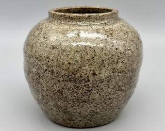 May include: A small, round, ceramic vase with a speckled brown and white glaze.