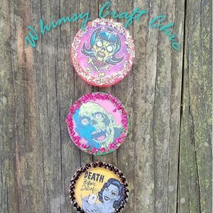 May include: Five round, colorful, resin-coated, decorative coasters with various Halloween-themed images and text. The coasters feature images of a zombie, a woman with a skull and crossbones, a woman with a phone, and a raven. The text on the coasters includes "Death Before Decaf", "In a world full of Kardashians be a Morticia", and "There's a little Witch in all of us".