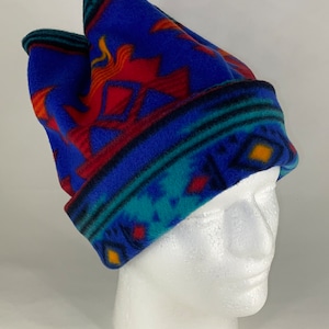 May include: Blue fleece beanie with a colorful geometric pattern. The pattern features red, yellow, turquoise, and black accents.