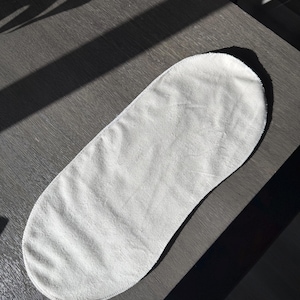 May include: A white oval-shaped baby changing mat with a soft, plush texture. The mat is made of a soft, absorbent material and is designed to protect your baby's delicate skin.