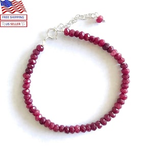 May include: A red gemstone bracelet with a silver clasp. The bracelet is made of small, faceted beads.