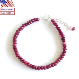 May include: A delicate bracelet featuring faceted, deep red gemstones strung on a silver chain. The bracelet has a simple design with a lobster clasp closure. The gemstones are a rich, burgundy color.