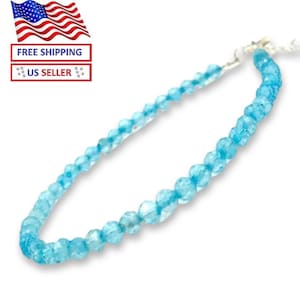 May include: A delicate bracelet featuring light blue, faceted beads. The beads are strung together, creating a continuous loop. The bracelet is designed to be worn around the wrist. The color is a bright, clear blue.