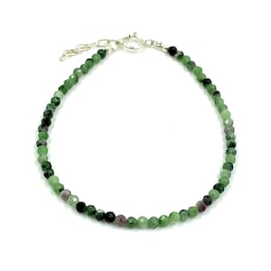 Op de afbeelding: Een armband van groene edelstenen met een zilveren sluiting. De armband is gemaakt van kleine, gefacetteerde kralen.