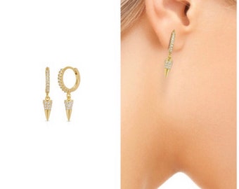 May include: Gold hoop earrings with a dangling, pointed, crystal-encrusted spike.