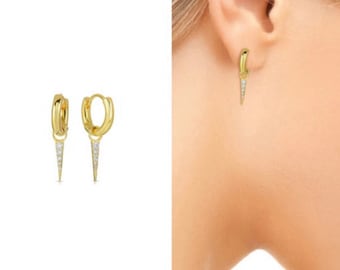 May include: Gold hoop earrings with a small, diamond-shaped pendant hanging from each hoop.