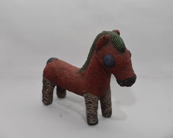 May include: A red, green, and blue beaded horse figurine. The horse is standing on all four legs and has a long mane and tail.