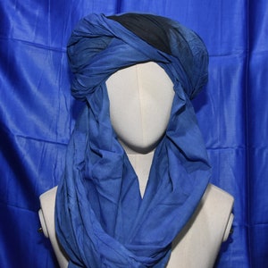 May include: A blue and black turban style head covering. The turban is made of a soft, flowing fabric and is tied in a loose knot at the top.