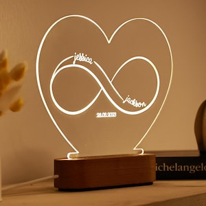 May include: A heart-shaped acrylic night light with an infinity symbol and the names "jessica" and "jackson" inscribed. The date "28.03.2023" is also inscribed on the light.