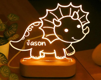 Könnte beinhalten: Eine weiße Umrandung eines Comic-Triceratops mit dem Namen "Jason" auf der Seite, von hinten mit einem warmen Licht beleuchtet. Der Dinosaurier ist auf einem Holzsockel montiert.