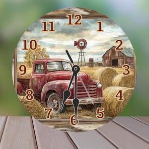 May include: Round wall clock featuring a rustic farm scene with a red pickup truck, hay bales, and a barn. The clock face has large, easy-to-read numbers and black clock hands. The clock is set against a blurred green background.