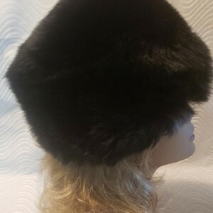 May include: A black faux fur hat with a wide brim. The hat is worn on a mannequin with blonde hair.