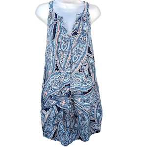 May include: Sleeveless dress with a paisley pattern in shades of blue, navy, and peach. The dress features a V-neckline and a flowing, tiered design. The fabric appears lightweight and suitable for warm weather.