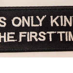 Op de afbeelding: Zwart rechthoekig embleem met witte geborduurde tekst: "IT'S ONLY KINKY THE FIRST TIME". De patch heeft een gestikte rand en is waarschijnlijk bedoeld om op kleding of accessoires te naaien.