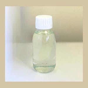 May include: A clear glass bottle with a white screw-on cap. The bottle is filled with a light yellow liquid.