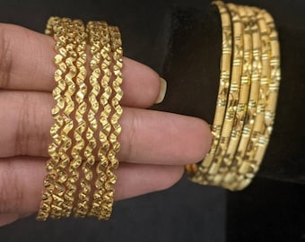 May include: A set of six gold-toned bangles with a textured, wavy design. The bangles are stacked on top of each other.