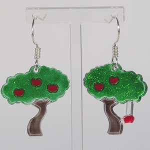 Peut inclure: Une paire de boucles d'oreilles pendantes en forme de pommiers verts pailletés avec des pommes rouges. Une boucle d'oreille a une pomme rouge pendante sur une chaîne argentée.