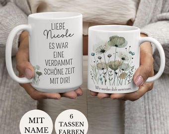 Może przedstawiać: Dwa białe ceramiczne kubki z czarnym tekstem i ilustracjami kwiatów. Lewy kubek zawiera niemiecki tekst 'LIEBE NICOLE ES WAR EINE VERDAMMT SCHÖNE ZEIT MIT DIR!', a prawy kubek przedstawia motyw kwiatowy z napisem 'Wir werden dich vermissen.'