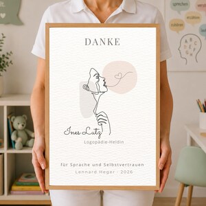 Könnte beinhalten: Ein gerahmter Druck mit einer schwarzen Strichzeichnung eines Profils, das eine Herzform bläst. Der Text lautet DANKE, Ines Lutz, Logopädie-Heldin, für Sprache und Selbstvertrauen und Lennard Heger 2026, ergänzt durch weiche pfirsichfarbene und graue Formen.