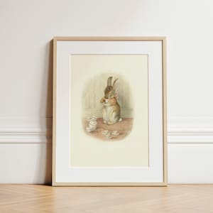 Puede incluir: Ilustración vintage enmarcada de un conejo marrón tomando té, rodeado de tazas de té en miniatura y una tetera. El conejo lleva un lazo rosa. La obra de arte está enmarcada en madera clara.